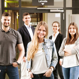 Gruppe Junger Menschen im Flur vor einem Lehrsaal