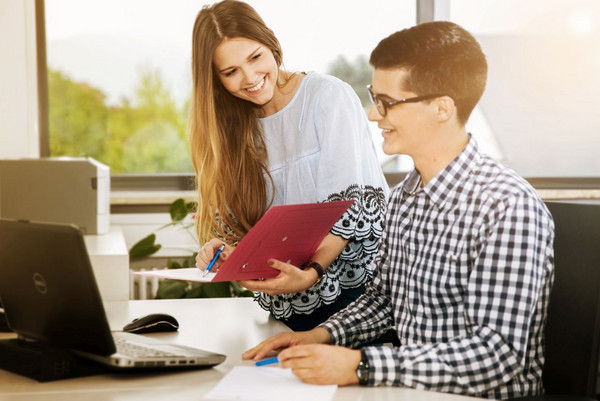 Studentin mit einer Umlaufmappe und Student vor einem Laptop